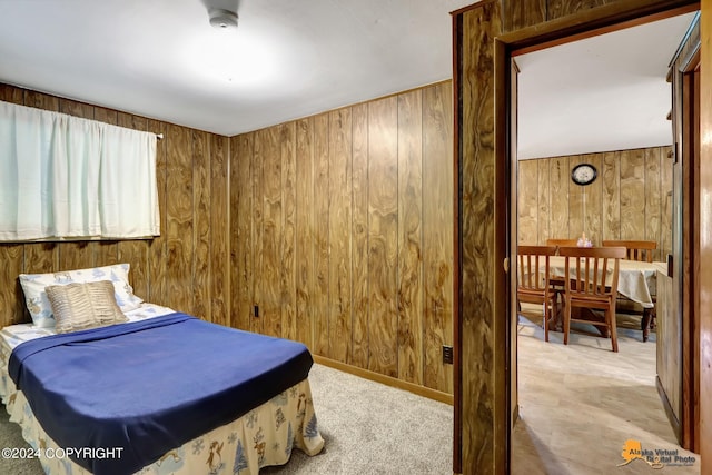 carpeted bedroom featuring wood walls