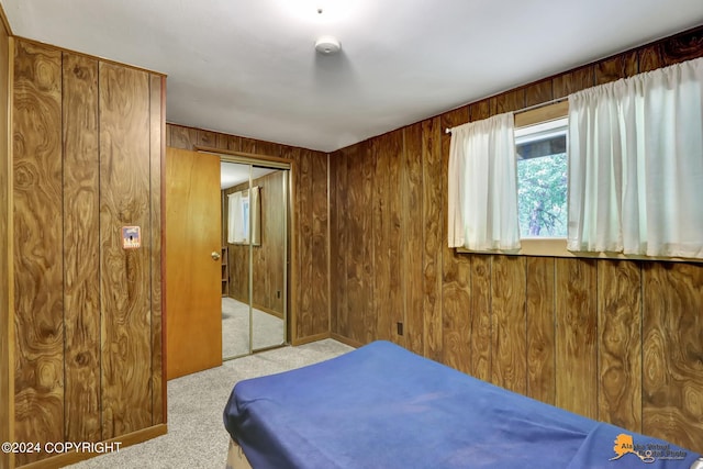 carpeted bedroom with a closet and wooden walls