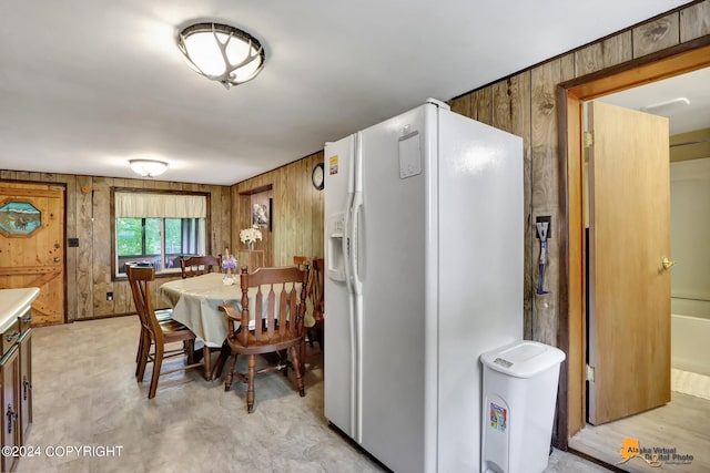 kitchen with wooden walls and white fridge with ice dispenser