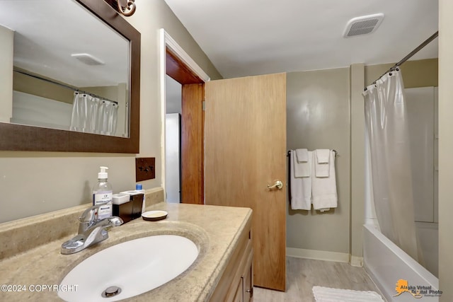 bathroom with hardwood / wood-style floors, vanity, and shower / bathtub combination with curtain