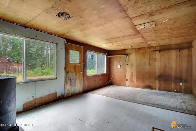 unfurnished room featuring water heater and wood walls