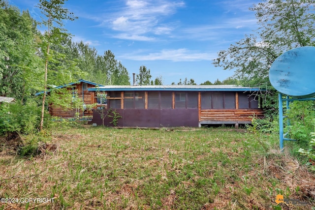 back of property with a sunroom and a lawn