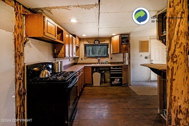 kitchen featuring hanging light fixtures, dark hardwood / wood-style flooring, black gas range oven, and sink