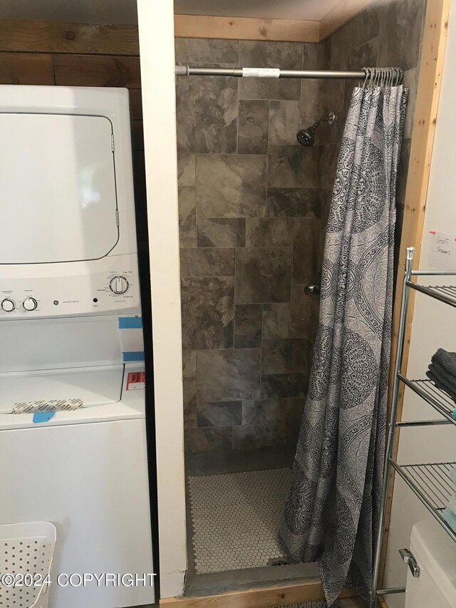 bathroom with stacked washer and dryer, toilet, and curtained shower