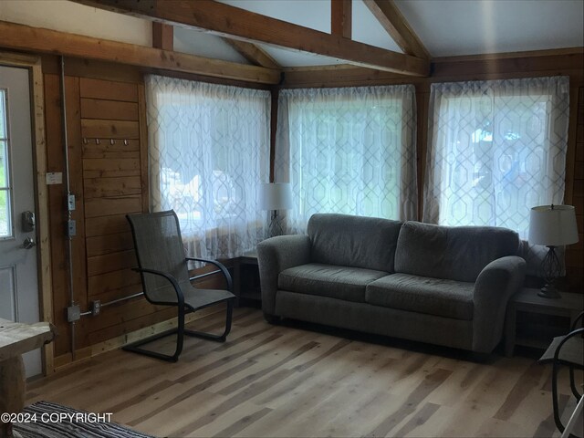 living room with wood walls, wood-type flooring, and vaulted ceiling with beams