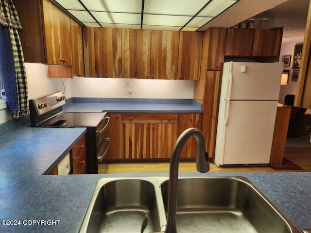 kitchen featuring white refrigerator, stainless steel electric stove, and sink