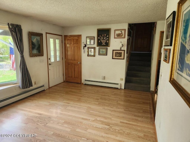 entrance foyer with plenty of natural light, baseboard heating, light hardwood / wood-style flooring, and a textured ceiling