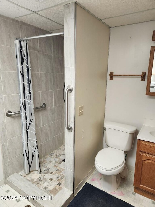 bathroom with vanity, a paneled ceiling, a shower with shower curtain, tile patterned floors, and toilet