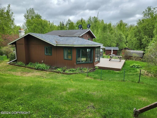 back of property featuring a deck and a lawn