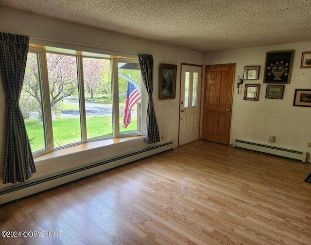 entryway featuring light wood-type flooring, a baseboard heating unit, and a textured ceiling