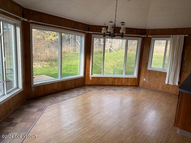 unfurnished sunroom with lofted ceiling, a notable chandelier, and a wealth of natural light