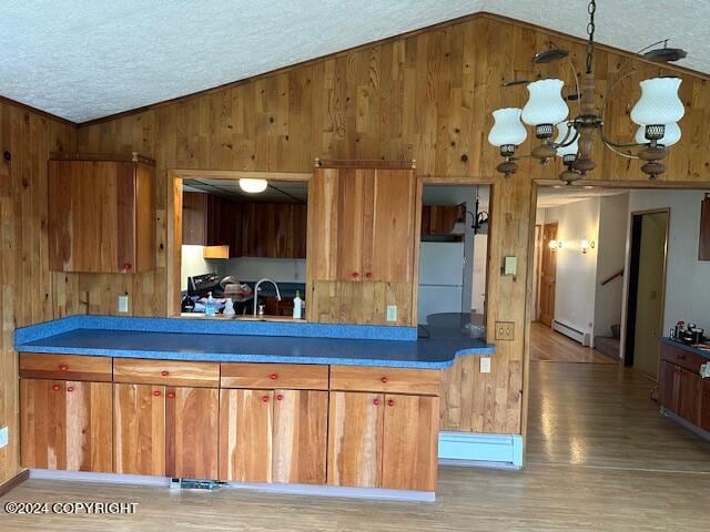 kitchen featuring white refrigerator, wood-type flooring, lofted ceiling, a baseboard heating unit, and a textured ceiling