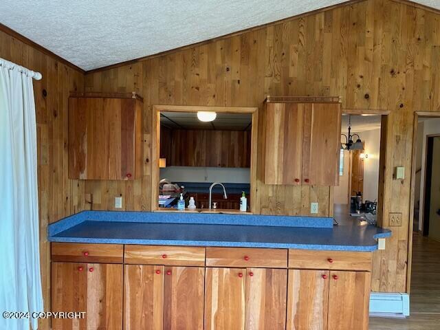 kitchen with wood walls, crown molding, hardwood / wood-style floors, and lofted ceiling