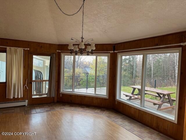 unfurnished sunroom featuring plenty of natural light, an inviting chandelier, and baseboard heating