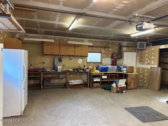 basement featuring a workshop area and white fridge