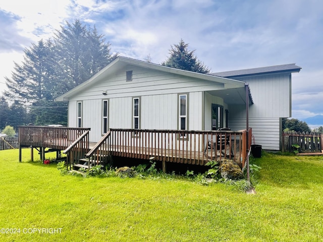 back of house featuring a lawn and a deck