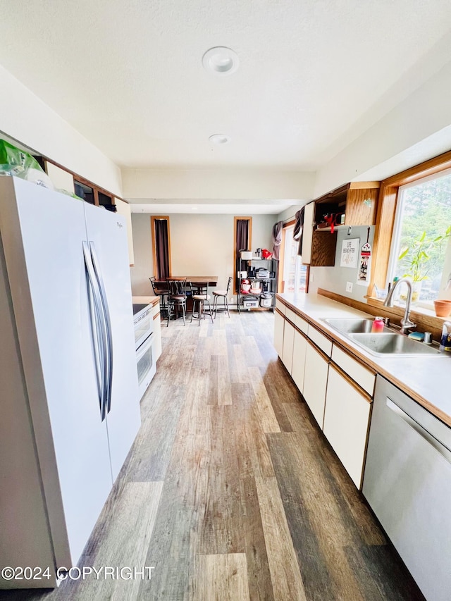 kitchen featuring sink, hardwood / wood-style flooring, white refrigerator, white cabinets, and stainless steel dishwasher