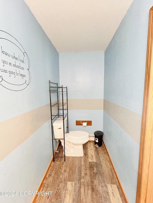 bathroom featuring toilet, hardwood / wood-style floors, and a baseboard heating unit