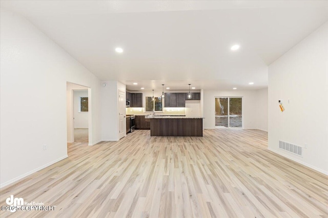 unfurnished living room with sink, vaulted ceiling, and light wood-type flooring