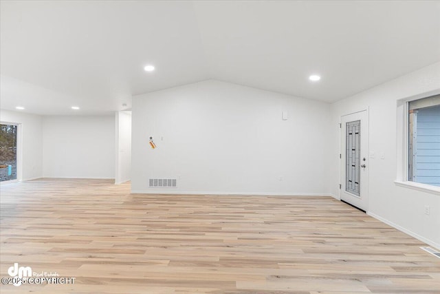 spare room with vaulted ceiling and light wood-type flooring