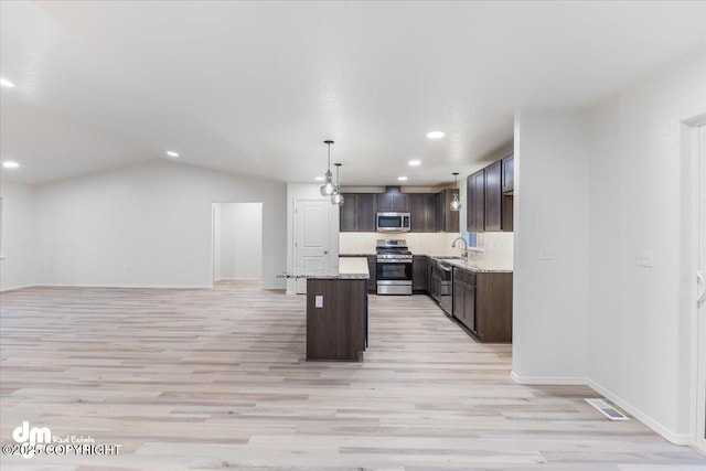 kitchen with pendant lighting, sink, appliances with stainless steel finishes, a center island, and light wood-type flooring