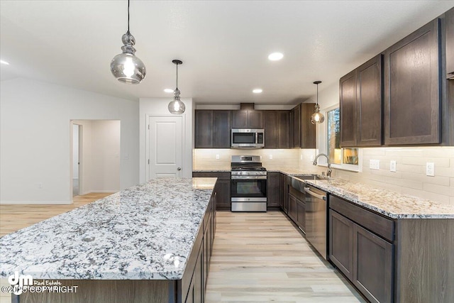 kitchen featuring stainless steel appliances, sink, pendant lighting, and dark brown cabinetry