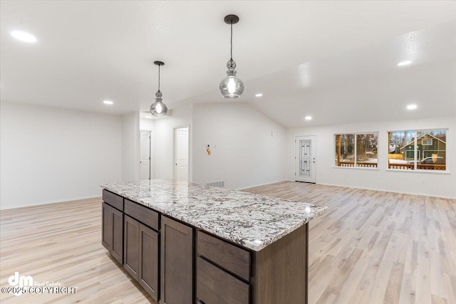 kitchen featuring lofted ceiling, dark brown cabinets, hanging light fixtures, light hardwood / wood-style flooring, and light stone countertops