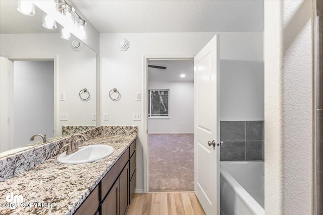 bathroom with hardwood / wood-style floors, vanity, and a washtub