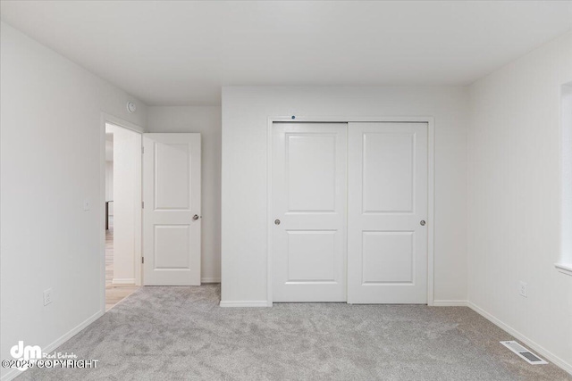 unfurnished bedroom with light carpet and a closet