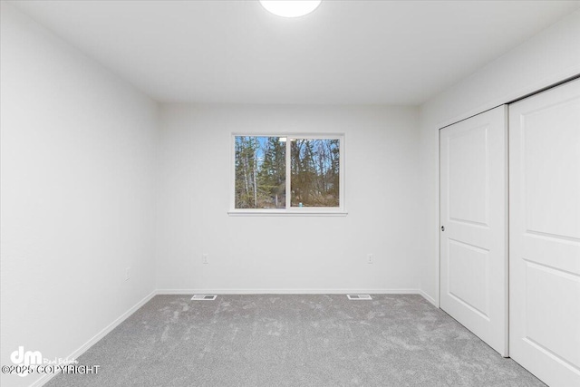 unfurnished bedroom with a closet and light carpet