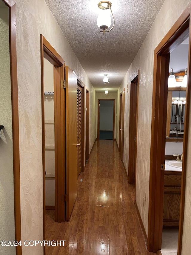 hallway with sink, hardwood / wood-style floors, and a textured ceiling