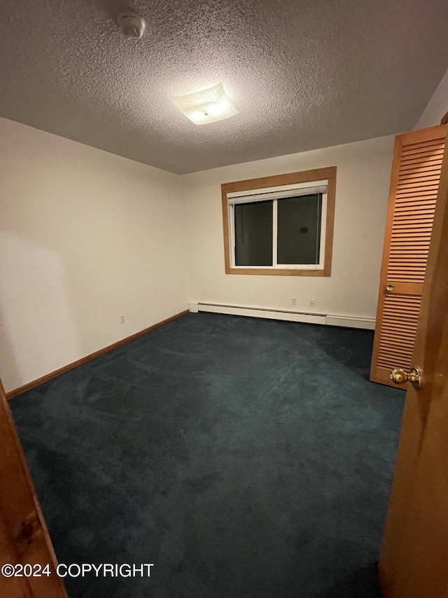 empty room featuring a textured ceiling and dark colored carpet