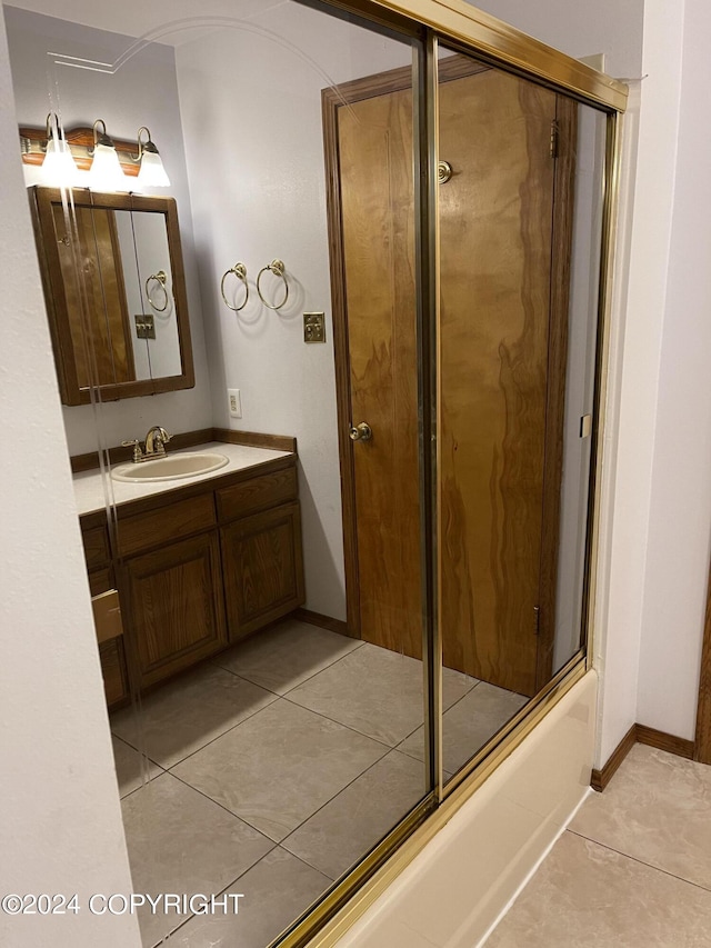 bathroom with enclosed tub / shower combo, vanity, and tile patterned flooring