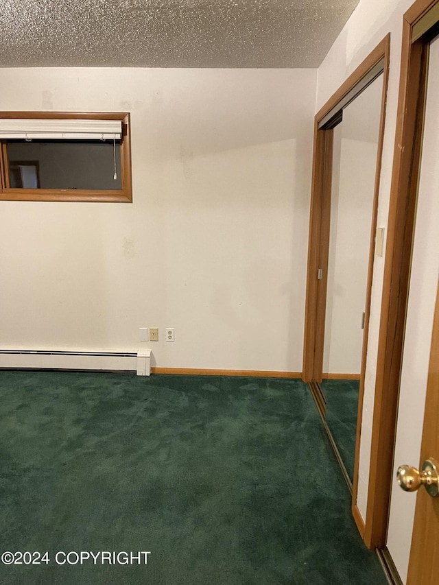 spare room with a baseboard radiator, a textured ceiling, and dark colored carpet