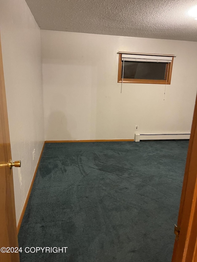 carpeted empty room featuring a textured ceiling and baseboard heating