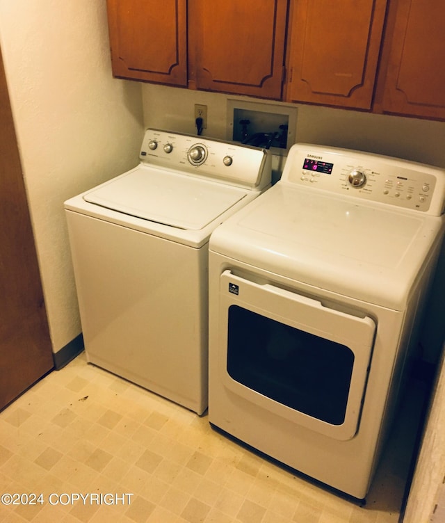 clothes washing area with washer and dryer and cabinets