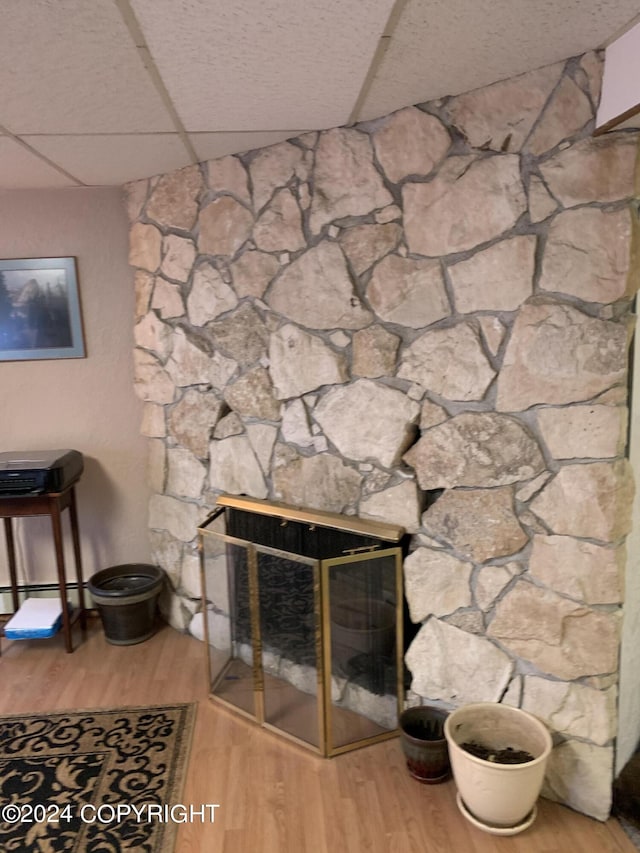 room details featuring baseboard heating, a paneled ceiling, wood-type flooring, and a fireplace