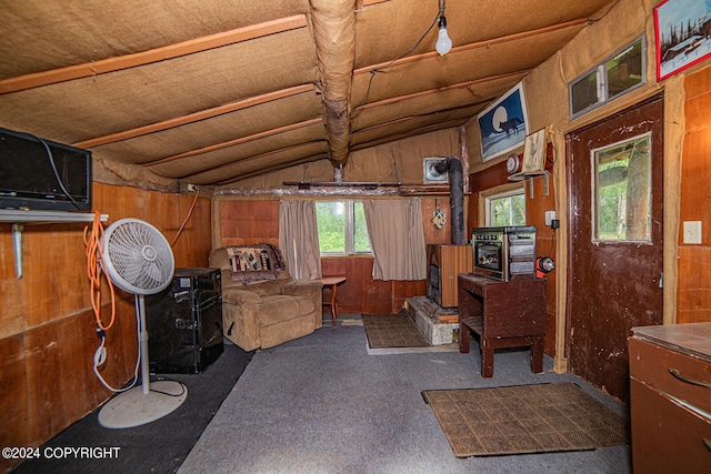 interior space featuring lofted ceiling, a wood stove, and wood walls