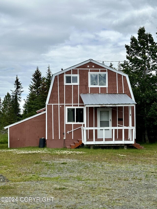 view of front facade featuring covered porch, a gambrel roof, and metal roof