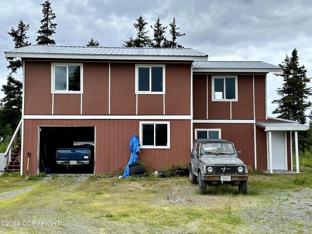 exterior space featuring driveway, an attached garage, and metal roof