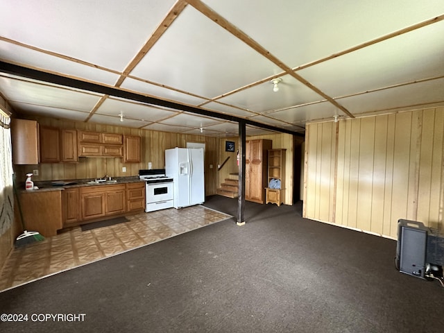 kitchen with a sink, wooden walls, brown cabinets, white appliances, and dark countertops