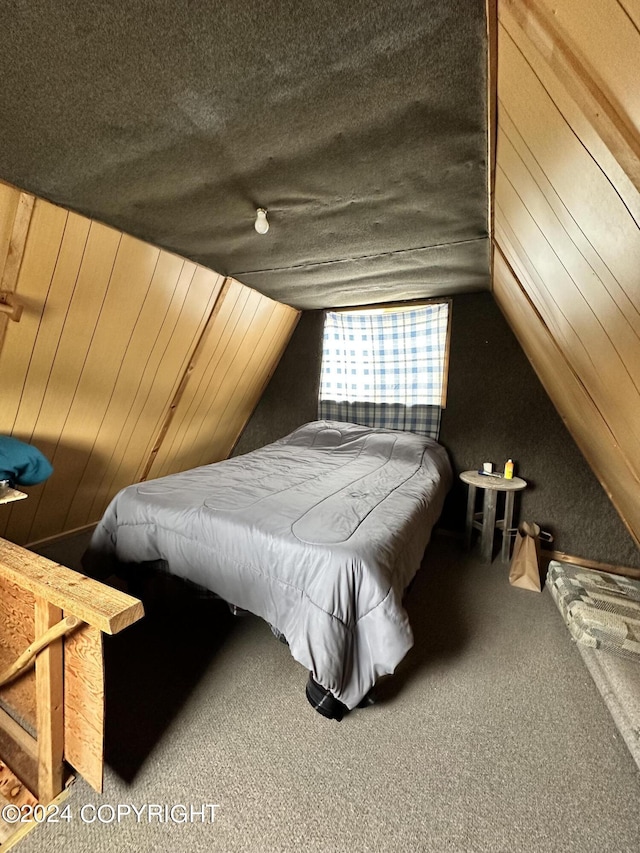 bedroom with lofted ceiling, wooden walls, carpet, and a textured ceiling