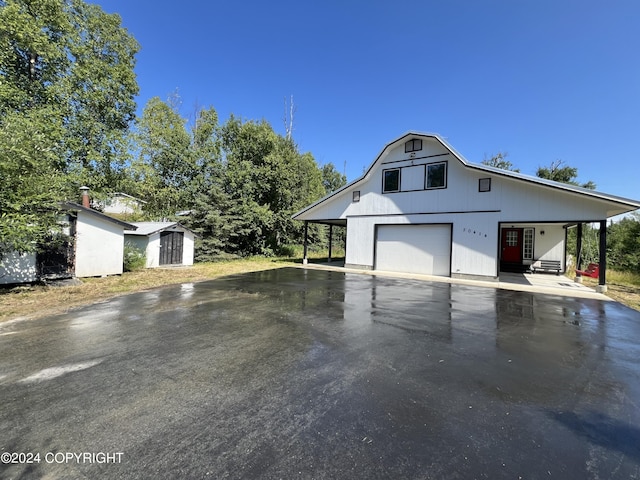 exterior space featuring a garage, a storage shed, aphalt driveway, an outbuilding, and a carport