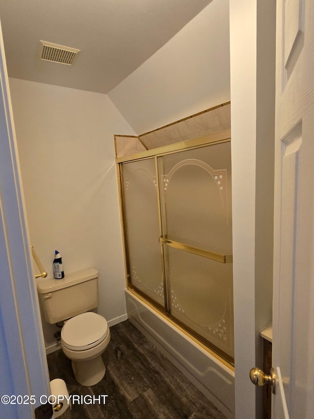 full bath featuring visible vents, toilet, shower / bath combination with glass door, wood finished floors, and vaulted ceiling