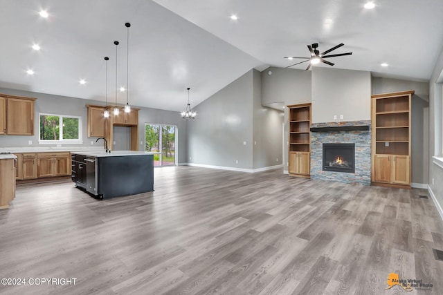 kitchen featuring pendant lighting, a fireplace, light hardwood / wood-style flooring, and a kitchen island with sink