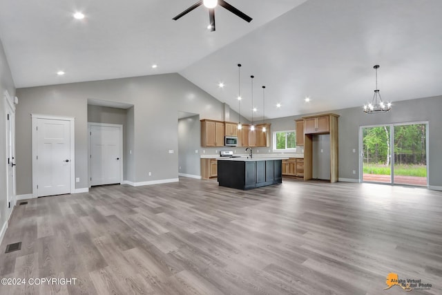 kitchen featuring ceiling fan with notable chandelier, appliances with stainless steel finishes, decorative light fixtures, light hardwood / wood-style floors, and a center island with sink