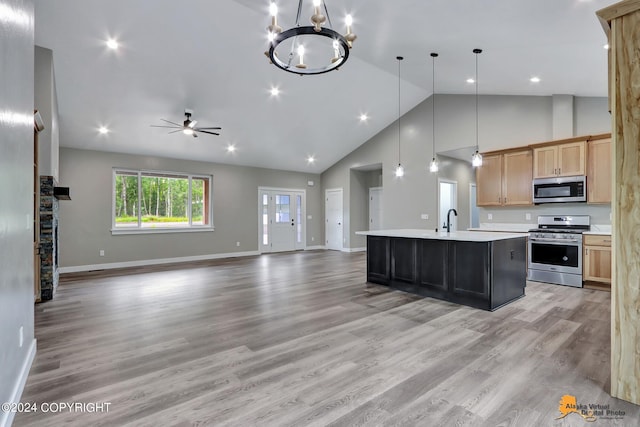 kitchen featuring a center island with sink, stainless steel appliances, light wood-type flooring, pendant lighting, and ceiling fan with notable chandelier