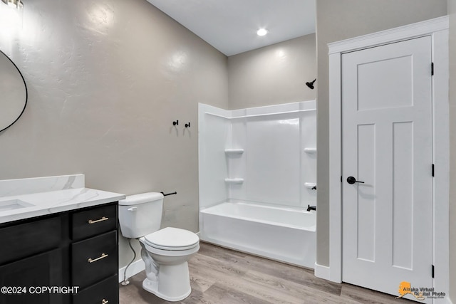 full bathroom featuring washtub / shower combination, toilet, hardwood / wood-style flooring, and vanity