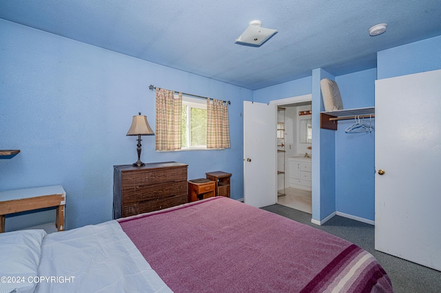 bedroom featuring dark carpet, a textured ceiling, and ensuite bathroom