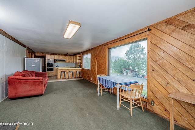 dining area featuring wooden walls and dark carpet